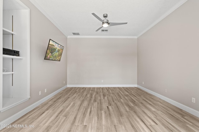 spare room featuring ornamental molding, baseboards, ceiling fan, visible vents, and wood finished floors