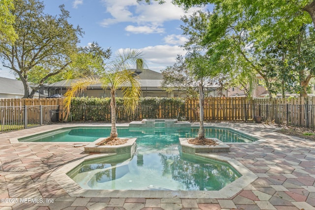 view of swimming pool with a fenced backyard, a pool with connected hot tub, and a patio