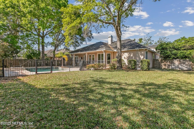 back of property featuring stucco siding, fence, a fenced in pool, a yard, and a chimney