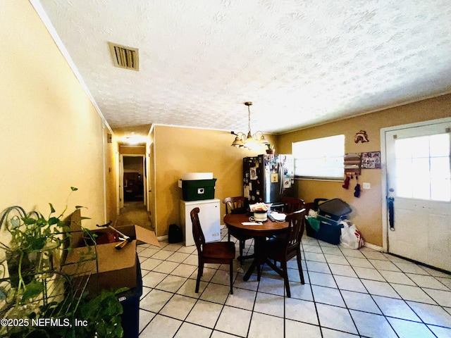 dining room featuring light tile patterned floors, visible vents, a textured ceiling, and a chandelier