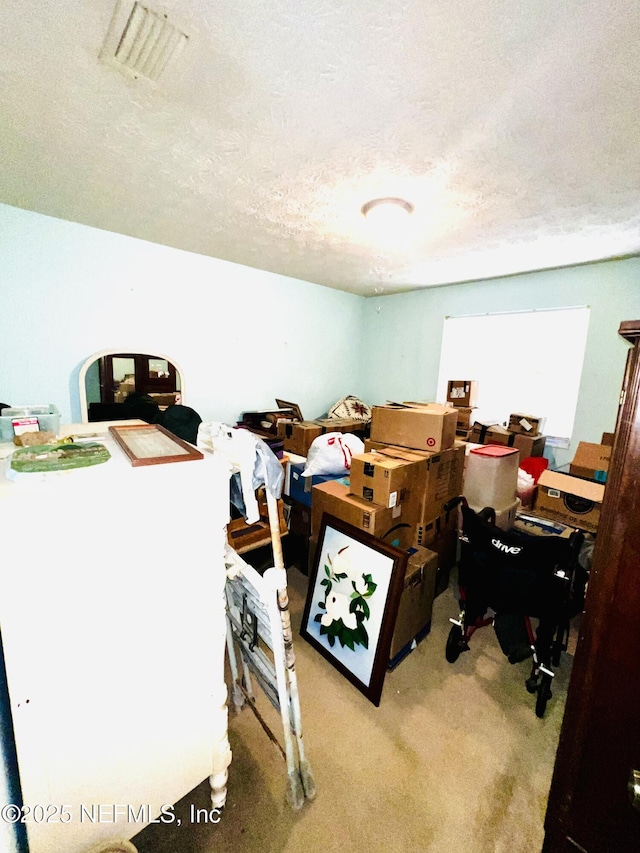 office area with visible vents, carpet floors, and a textured ceiling