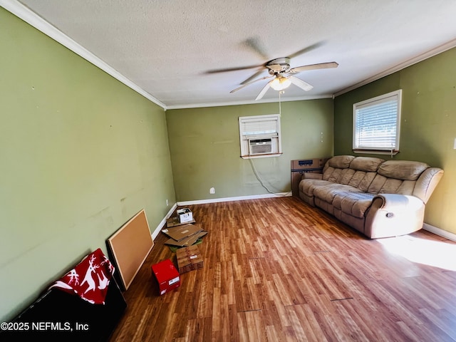 living room with a ceiling fan, a textured ceiling, wood finished floors, crown molding, and baseboards