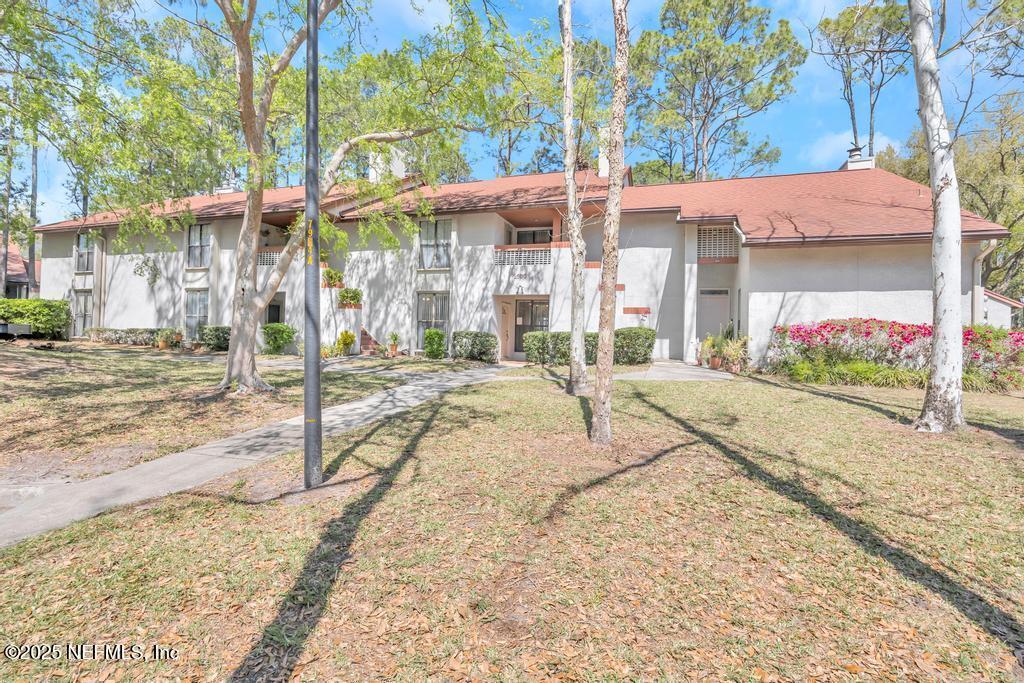 2505 Wood Hill Dr Unit 2505, Jacksonville, FL 32256 - view of front of property with stucco siding, a front lawn, and a chimney