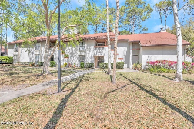 2505 Wood Hill Dr Unit 2505, Jacksonville, FL 32256 - view of front of property with stucco siding, a front lawn, and a chimney