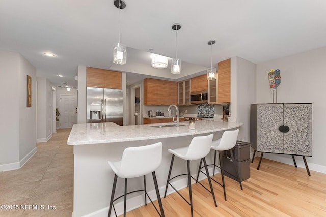 525 3rd St N Unit 210, Jacksonville Beach, FL 32250 - kitchen featuring a breakfast bar area, brown cabinetry, a peninsula, a sink, and stainless steel appliances