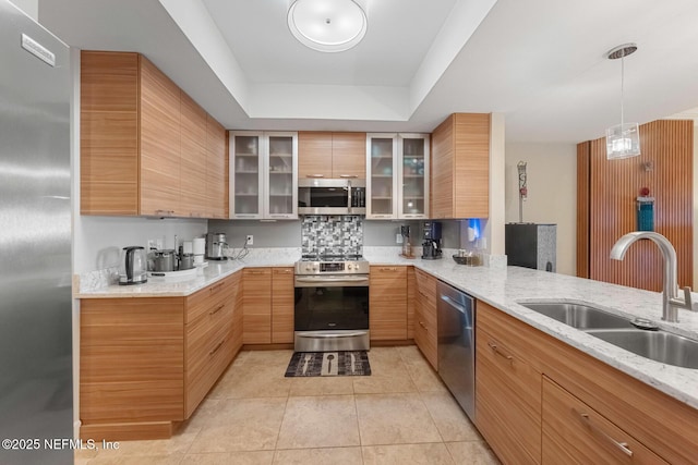 525 3rd St N Unit 210, Jacksonville Beach, FL 32250 - kitchen featuring light tile patterned floors, a tray ceiling, a sink, glass insert cabinets, and appliances with stainless steel finishes