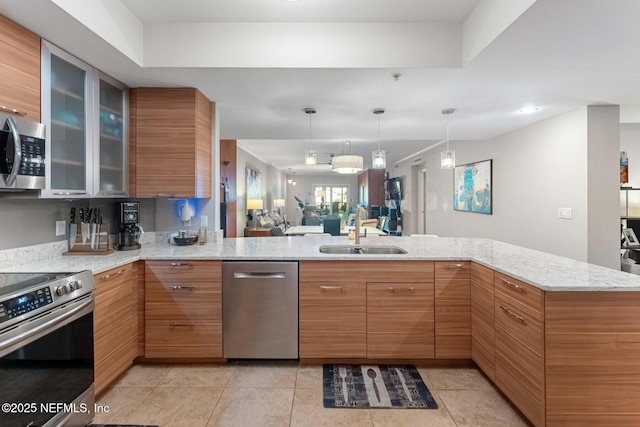 525 3rd St N Unit 210, Jacksonville Beach, FL 32250 - kitchen with a sink, appliances with stainless steel finishes, glass insert cabinets, light stone countertops, and hanging light fixtures