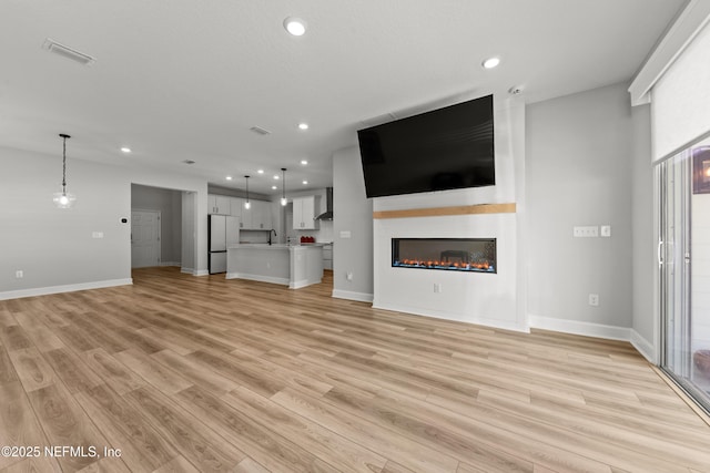 95058 Rocky Pl, Fernandina Beach, FL 32034 - unfurnished living room with visible vents, recessed lighting, a large fireplace, light wood-style floors, and baseboards