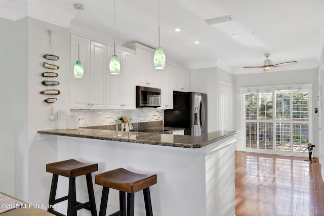 2114 Gail Ave Unit A, Jacksonville Beach, FL 32250 - kitchen with stainless steel appliances, a kitchen bar, backsplash, a peninsula, and white cabinetry