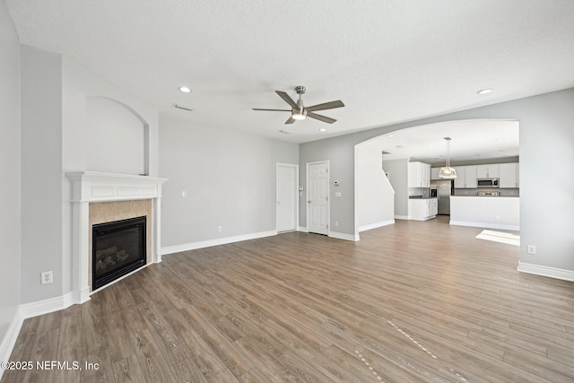 unfurnished living room with light wood finished floors, baseboards, recessed lighting, a fireplace, and a ceiling fan