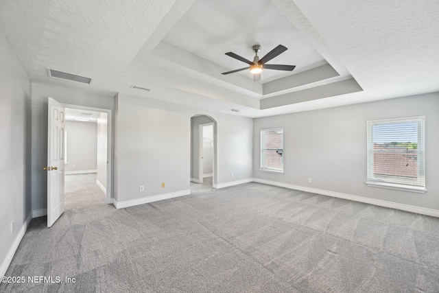 unfurnished bedroom featuring visible vents, baseboards, carpet floors, a textured ceiling, and a raised ceiling
