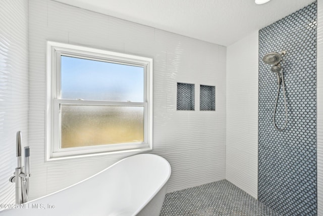 bathroom featuring a freestanding bath, a textured ceiling, and tiled shower