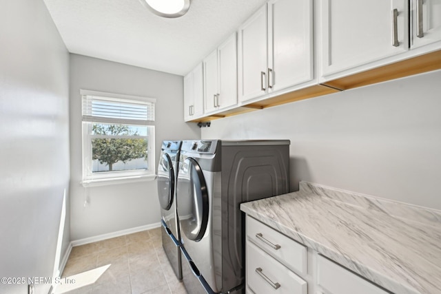laundry room featuring light tile patterned floors, washing machine and dryer, cabinet space, and baseboards