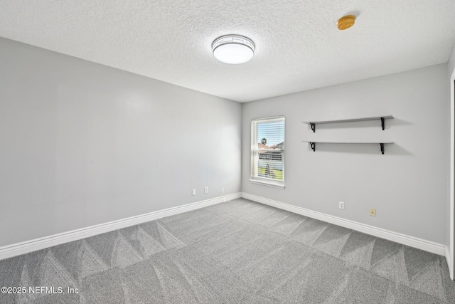 carpeted empty room with baseboards and a textured ceiling