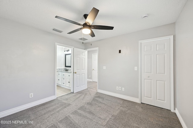 unfurnished bedroom with visible vents, baseboards, a sink, ensuite bathroom, and light colored carpet