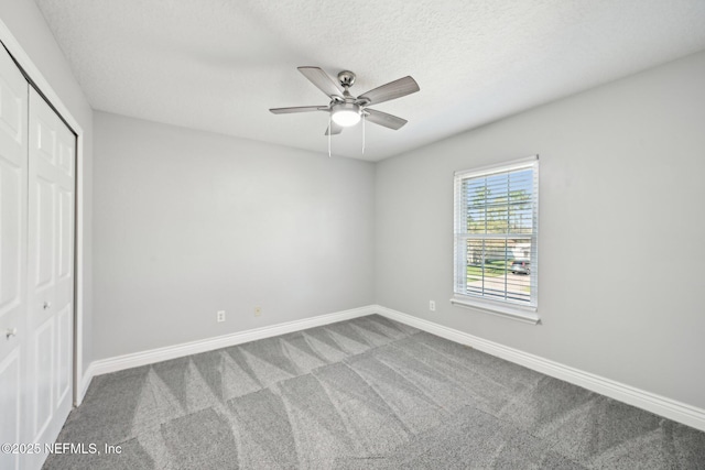 unfurnished bedroom featuring baseboards, ceiling fan, a closet, a textured ceiling, and carpet flooring