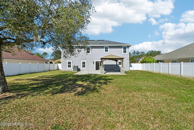 rear view of property featuring a fenced backyard, a lawn, a gazebo, and a patio