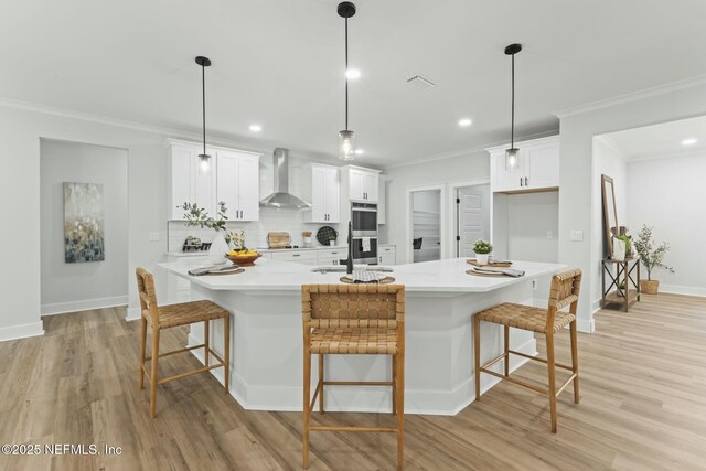 85172 Southern Creek Blvd, Fernandina Beach, FL 32034 - kitchen with wall chimney range hood, crown molding, double oven, light wood-style flooring, and decorative backsplash