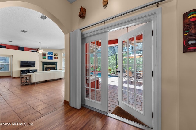 5266 Camelot Forest Dr, Jacksonville, FL 32258 - entryway featuring a lit fireplace, arched walkways, a textured ceiling, a ceiling fan, and visible vents
