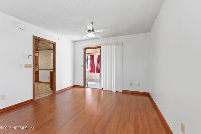 spare room featuring baseboards, a textured ceiling, ceiling fan, and light wood finished floors