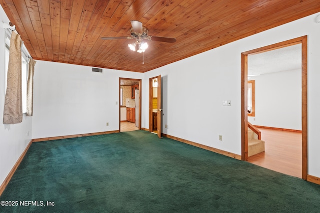 empty room with a ceiling fan, visible vents, carpet floors, stairs, and wood ceiling