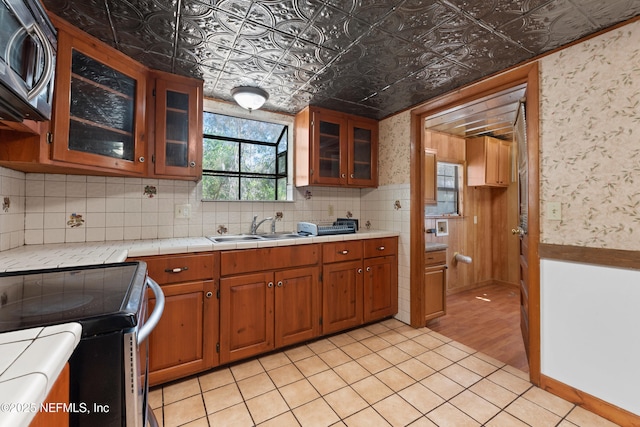 kitchen with brown cabinetry, stainless steel appliances, an ornate ceiling, and a sink