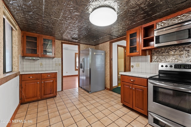 kitchen featuring stainless steel appliances, an ornate ceiling, tile counters, and decorative backsplash