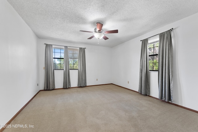 spare room with carpet flooring, a textured ceiling, baseboards, and ceiling fan