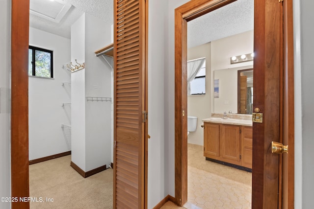 interior space featuring vanity, toilet, a closet, and a textured ceiling