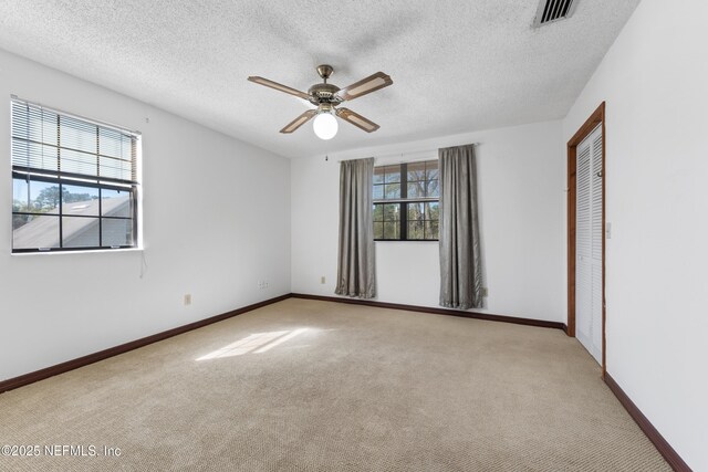 spare room featuring a ceiling fan, light colored carpet, visible vents, and baseboards