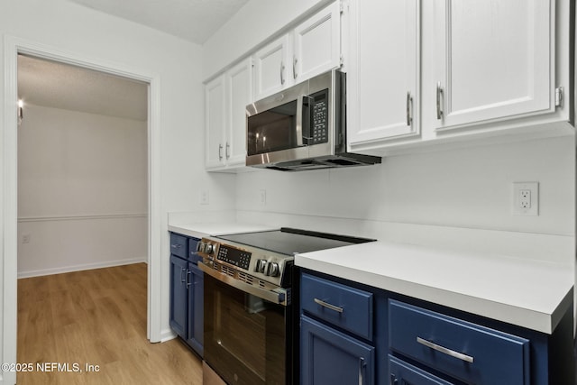 13706 Wm Davis Pkwy, Jacksonville, FL 32224 - kitchen featuring appliances with stainless steel finishes, blue cabinetry, white cabinetry, light wood-type flooring, and light countertops