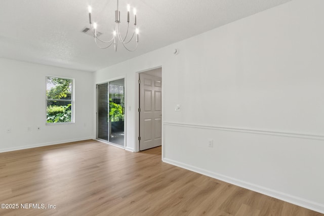 13706 Wm Davis Pkwy, Jacksonville, FL 32224 - empty room with a chandelier, light wood-style flooring, and a textured ceiling