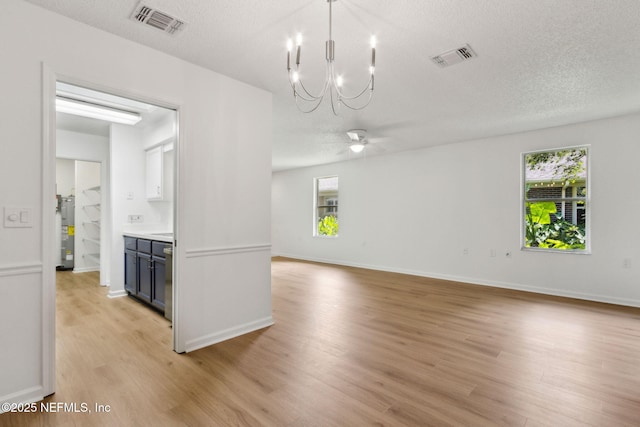 13706 Wm Davis Pkwy, Jacksonville, FL 32224 - unfurnished room with light wood-style flooring, healthy amount of natural light, a chandelier, a textured ceiling, and ceiling fan