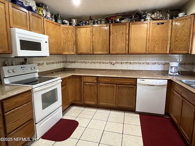 205 Harbor Dr, Palatka, FL 32177 - kitchen featuring brown cabinetry, decorative backsplash, white appliances, and light tile patterned floors
