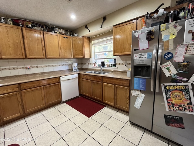 205 Harbor Dr, Palatka, FL 32177 - kitchen featuring brown cabinets, a sink, tasteful backsplash, stainless steel fridge, and white dishwasher