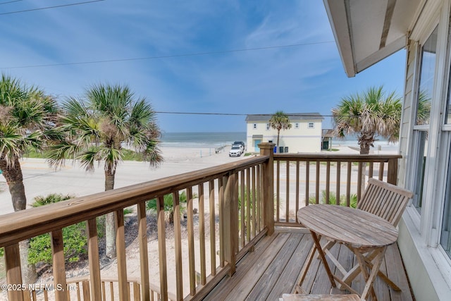 wooden terrace featuring a water view and a view of the beach