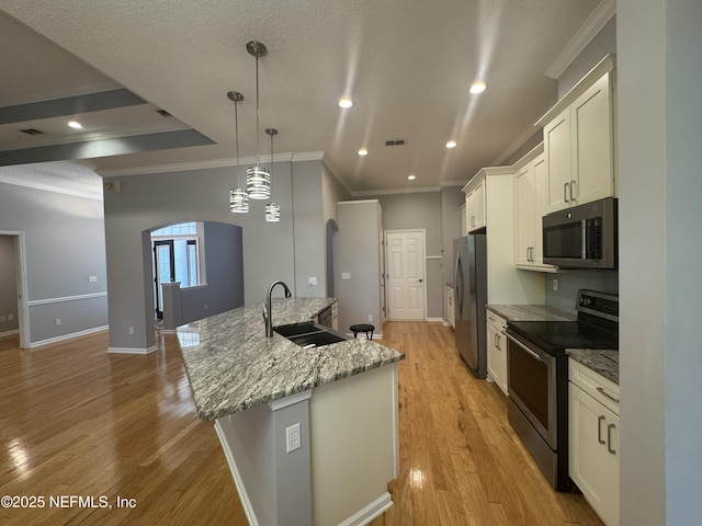 2924 Captiva Bluff Rd S, Jacksonville, FL 32226 - kitchen featuring white cabinetry, a sink, arched walkways, light wood-style flooring, and appliances with stainless steel finishes