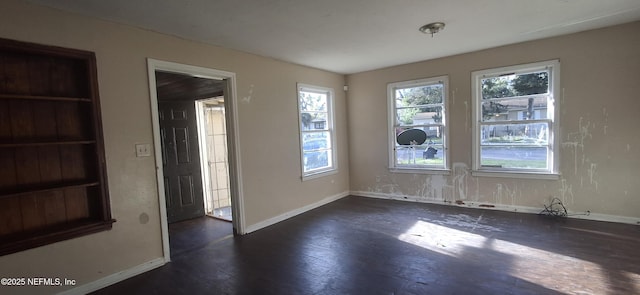 empty room with dark wood-type flooring and baseboards