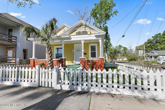 view of front of home featuring brick siding, covered porch, and a fenced front yard