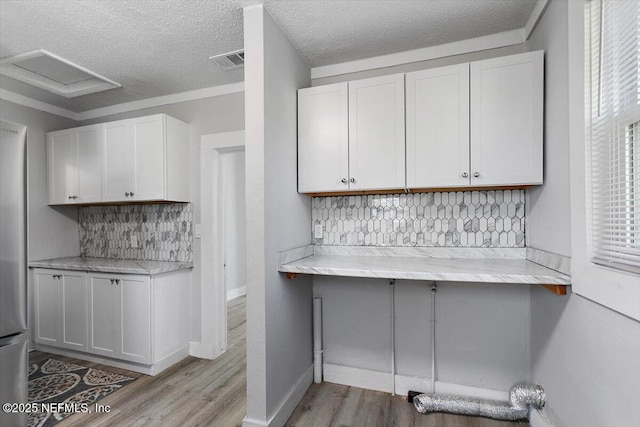 kitchen with visible vents, a textured ceiling, backsplash, white cabinetry, and light wood finished floors