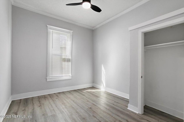 unfurnished bedroom with a closet, a textured ceiling, baseboards, and wood finished floors