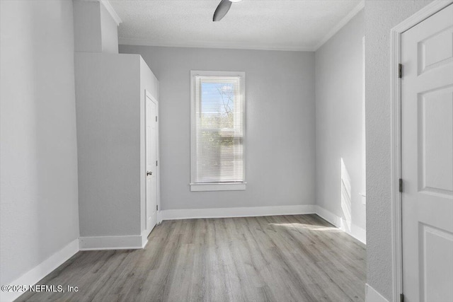 empty room featuring baseboards, a textured ceiling, wood finished floors, and crown molding