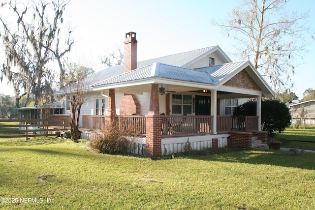 view of side of home featuring fence, metal roof, a yard, and a chimney