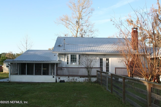 back of property featuring a lawn, a chimney, a sunroom, and fence
