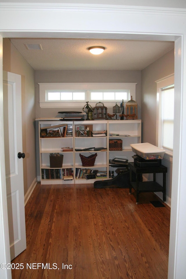 interior space featuring baseboards, visible vents, wood finished floors, and multiple windows