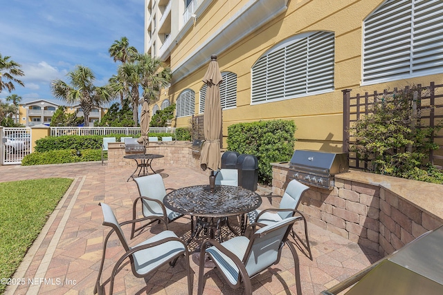 view of patio / terrace with fence, outdoor dining space, grilling area, and an outdoor kitchen