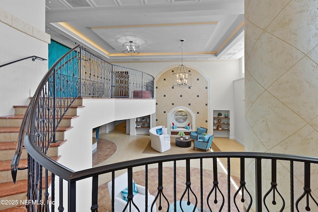 stairs featuring arched walkways, an inviting chandelier, visible vents, a raised ceiling, and a towering ceiling