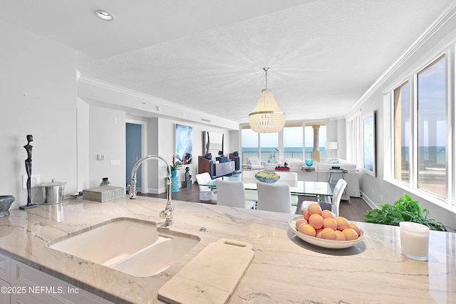 kitchen featuring open floor plan, a chandelier, ornamental molding, and a sink