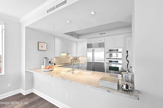 kitchen with appliances with stainless steel finishes, dark wood-style flooring, a sink, baseboards, and visible vents