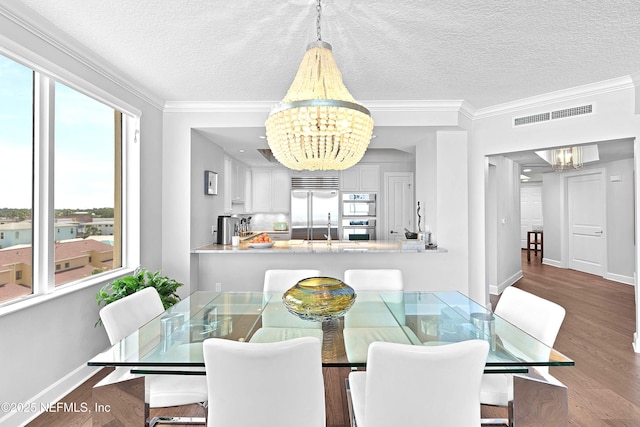 dining space featuring ornamental molding, a textured ceiling, visible vents, and a chandelier